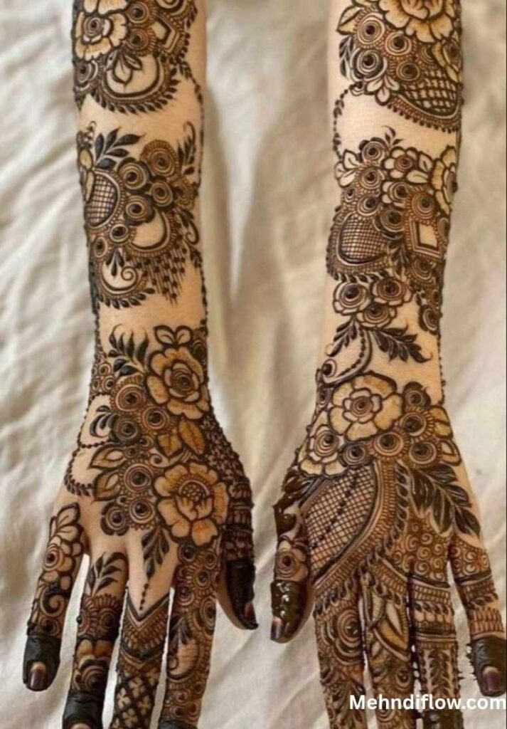 Back of two hands and forearms featuring dense bridal mehndi with prominent rose motifs and leafy vines.
