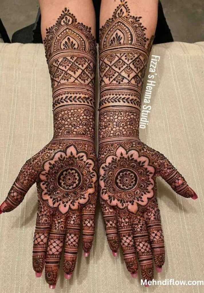 Two palms and forearms displaying symmetrical bridal mehndi with large central mandalas and intricate grid patterns.
