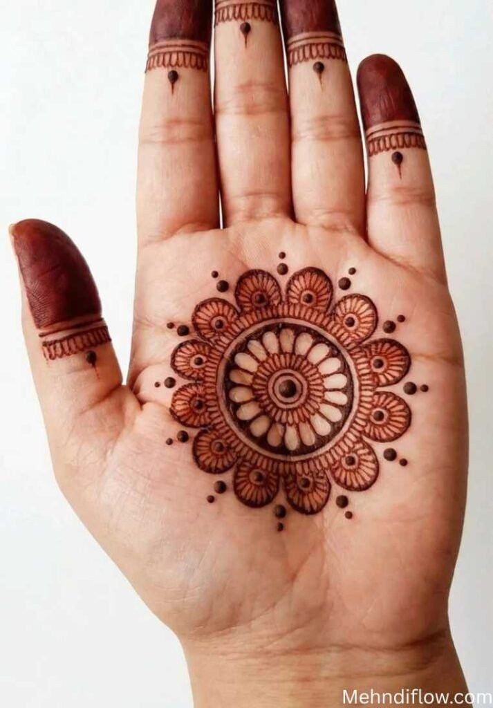 A palm-up hand displaying a clean, circular geometric mandala in the center of the palm, simple capped fingertip patterns, and a thick, detailed floral wrist cuff.