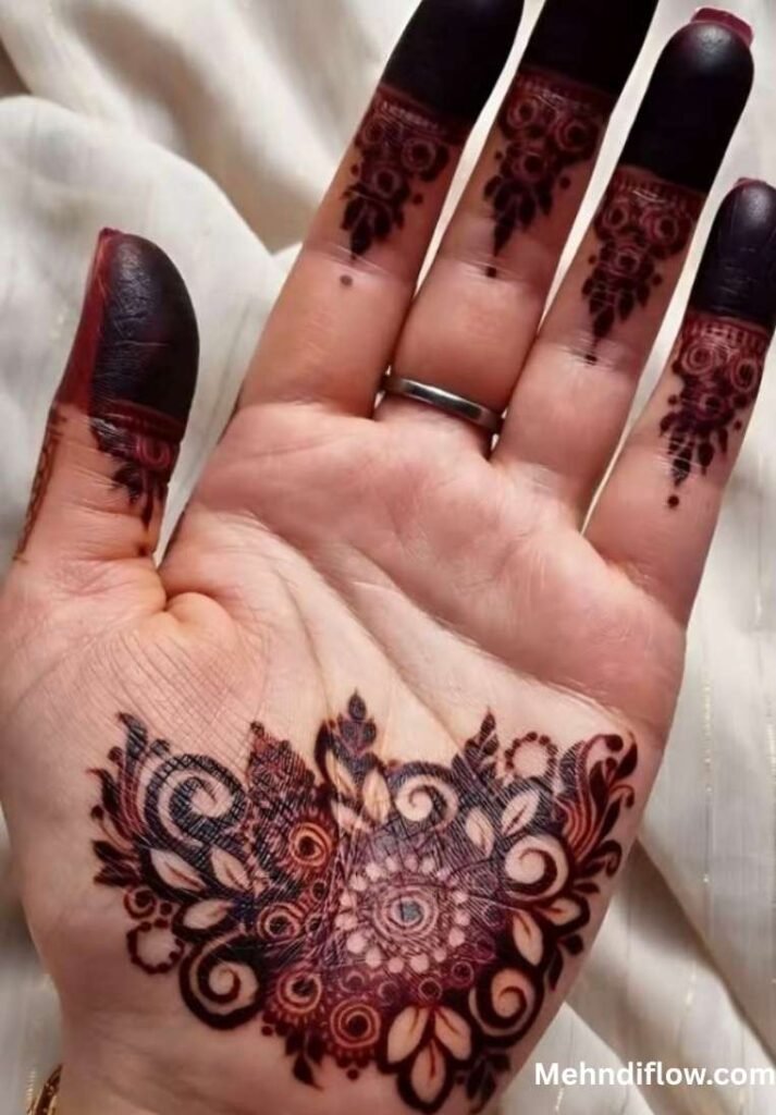 Open palm with solid dark henna on the fingertips and a prominent floral motif at the base of the hand.