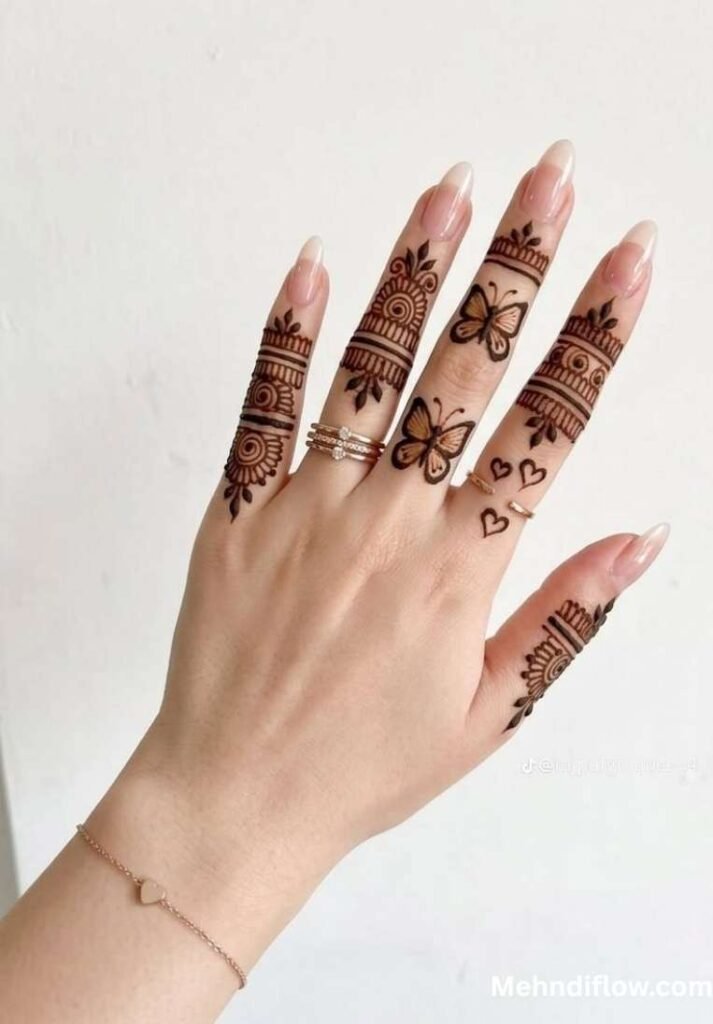 Hand against a white background featuring delicate finger mehndi with ring bands, leaf motifs, and small butterflies.