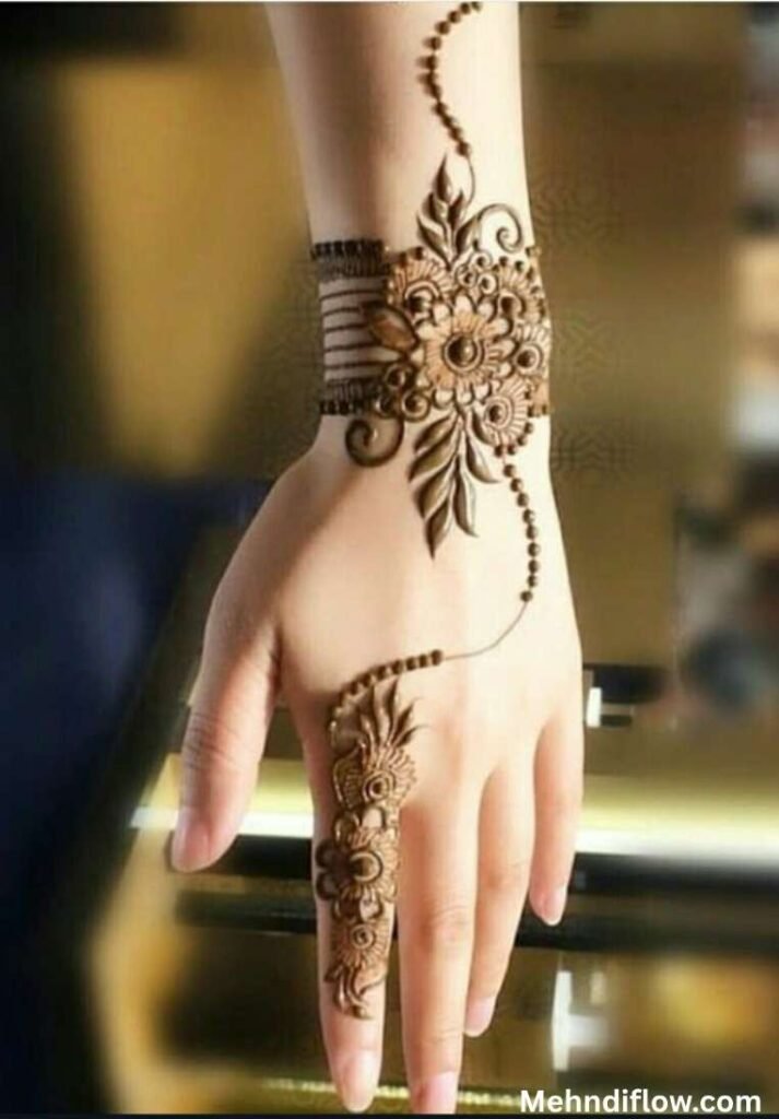 Elegant bracelet style mehndi design on the wrist with floral motifs and a trailing index finger pattern
