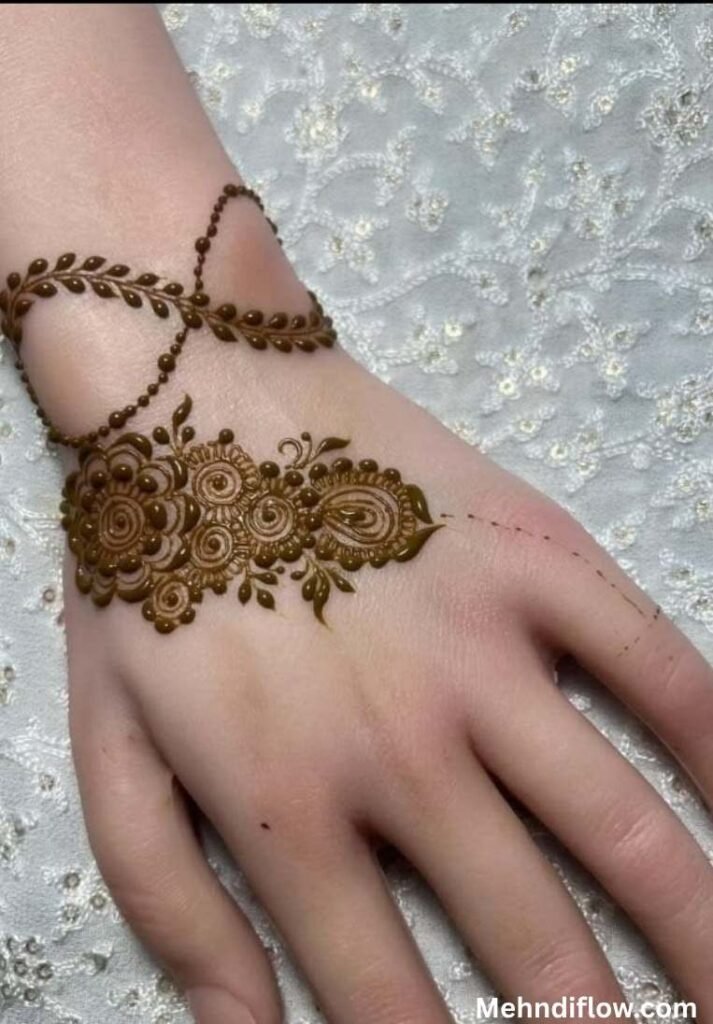 Close up of the back of a hand showcasing an intricate, elegant bracelet mehndi design with detailed floral motifs and paisleys, paired with a dainty, cross-over leafy vine pattern wrapping gracefully around the wrist