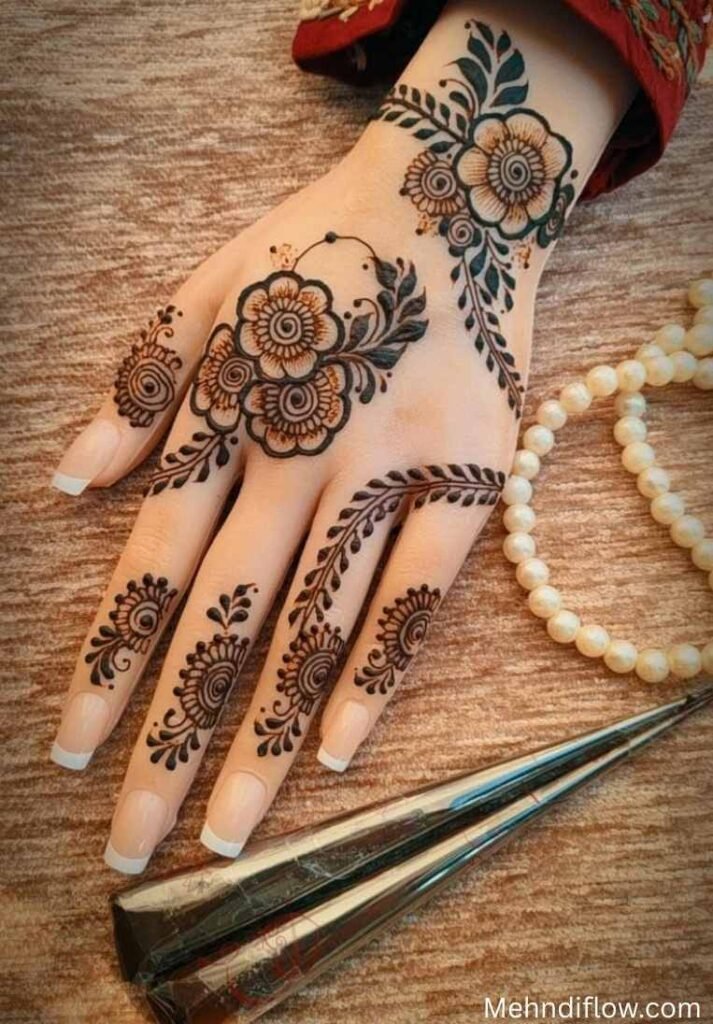 Arabic-style back hand mehndi design with complex floral motifs, a detailed wrist cuff, and a prominent leafy trail on the index finger. - Instagram Stylish Back Hand Mehndi Designs 