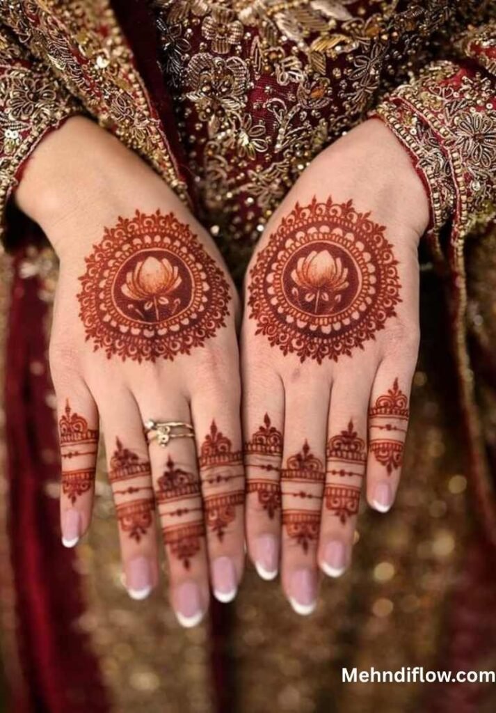 A pair of hands showcasing a vibrant floral tikki mehndi pattern, featuring a central lotus-inspired circular motif on the back of each hand, accented by delicate detailing on the fingers.