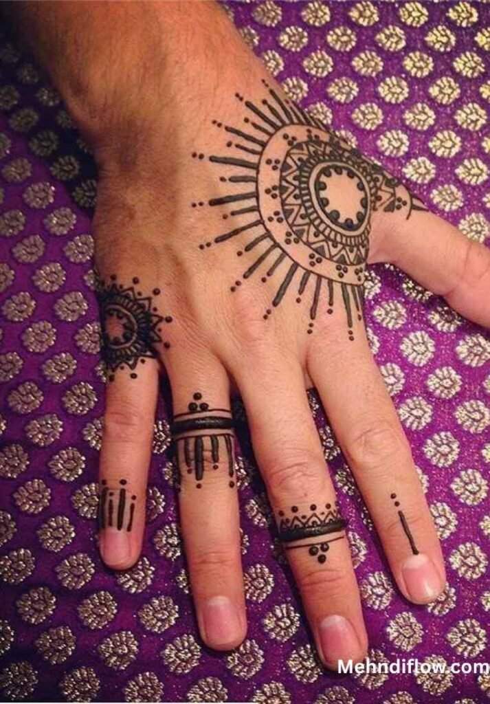 A hand featuring a sunburst-inspired mehndi design on the back of the hand, complemented by intricate, minimalist bands and vertical dot details on the fingers.