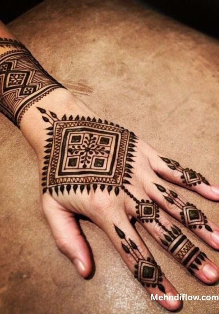A hand adorned with a bold, square-based geometric mehndi pattern, featuring a central tribal motif, a structured wrist cuff, and matching geometric accents on the fingers.