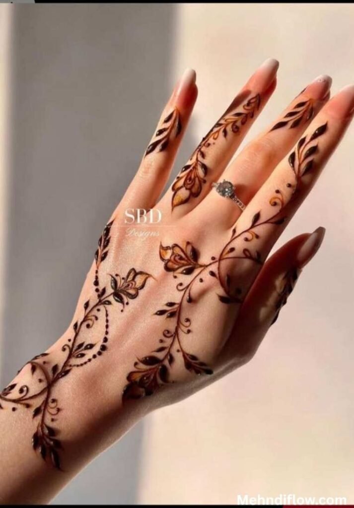 Elegant hand displaying flowing leaf vine henna patterns across the back of the hand.