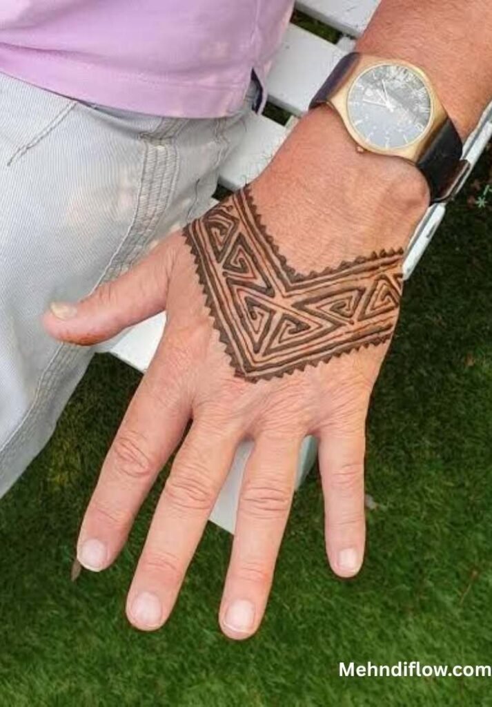 A man’s hand featuring a bold, angular geometric mehndi design on the back of the hand, styled like a wristband.