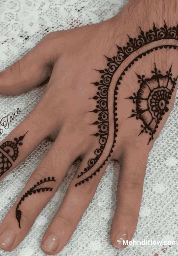 A hand displaying a minimalist, asymmetrical mehndi pattern that follows the side of the hand with intricate curved lines and small floral accents on the finger.