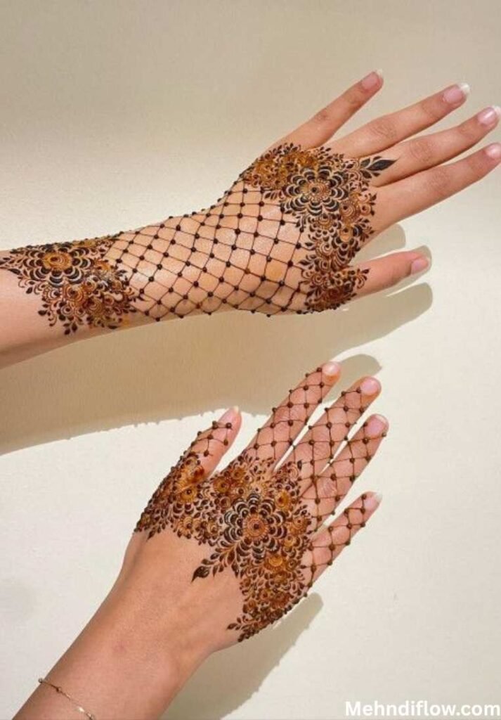 Hands showcasing a bold net-like henna design with floral detailing.
