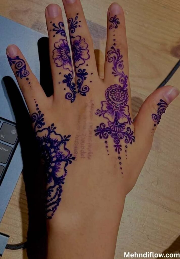 urple glitter finger mehndi design with detailed floral clusters and hanging dotted patterns on the back of the hand.