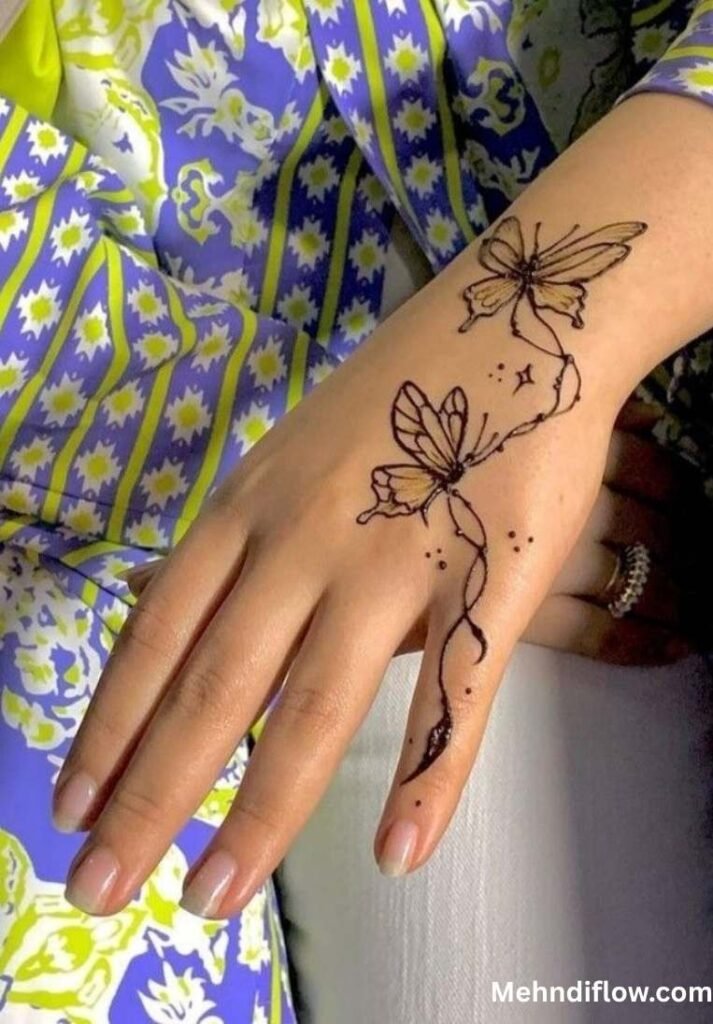 Simple outlined butterfly mehndi design with a delicate trailing vine on the back of the hand and index finger.