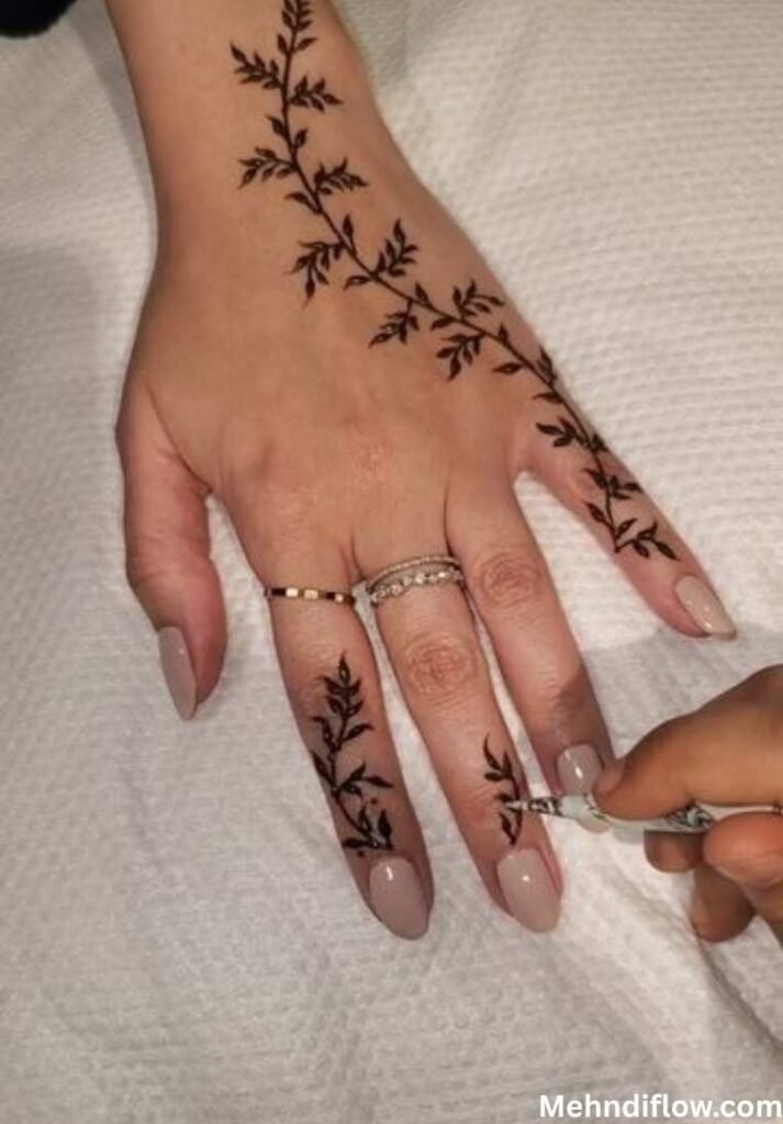 A hand showcasing a minimalist vine and leaf mehndi design along the finger.