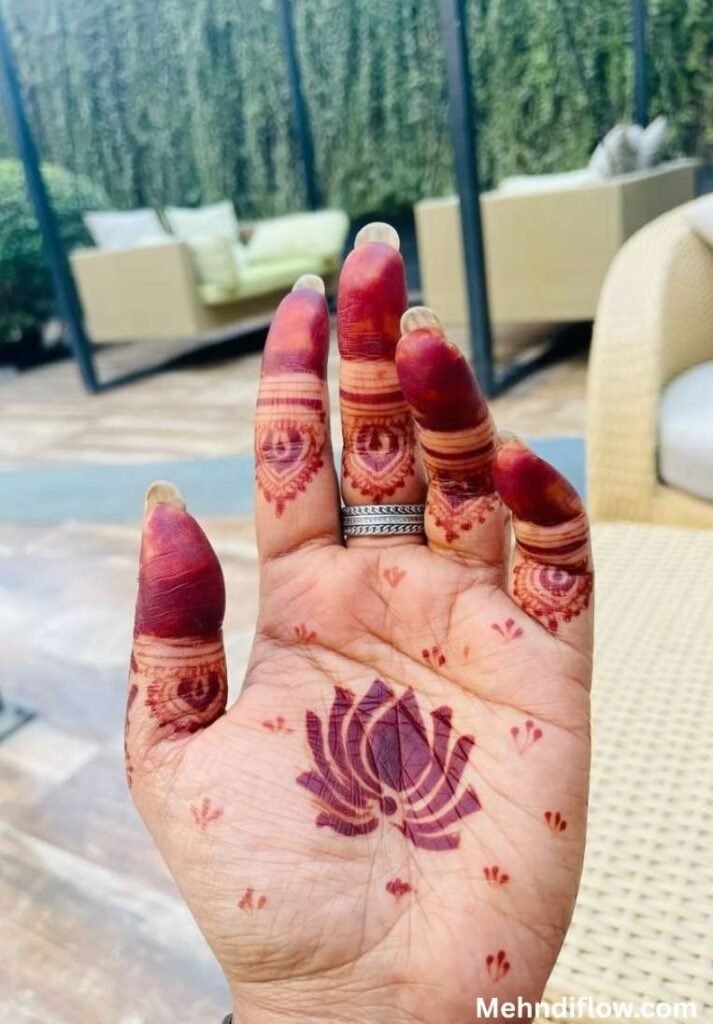 Minimalist 5-petal lotus henna design on a single palm with reddish-brown stained fingertips.