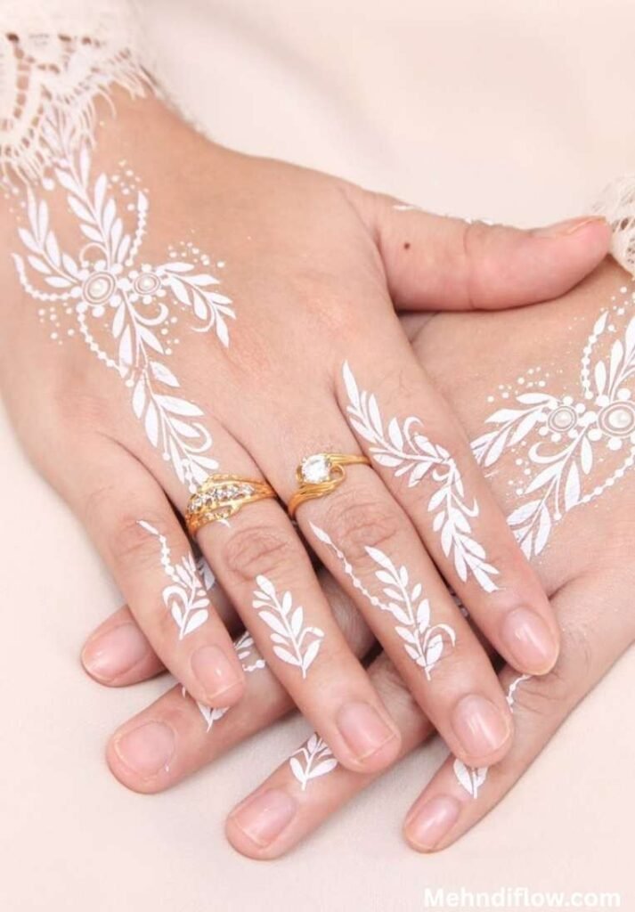 Delicate Arabic-style white henna design showcasing elegant, scattered leafy vines and dainty floral motifs flowing gracefully across the hands and down the fingers.