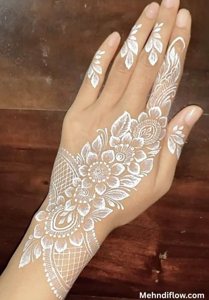 Bridal white mehndi design featuring a striking diagonal floral arrangement with shaded leaves and delicate mesh detailing on the back of the hand and fingers.