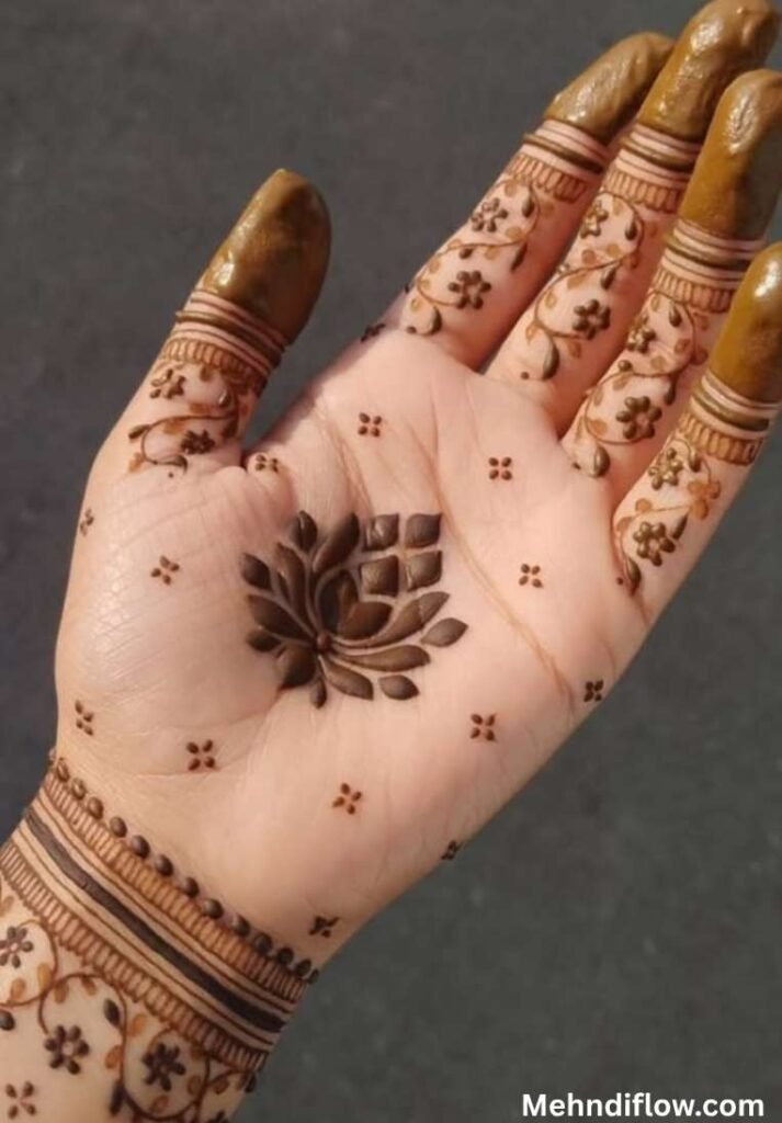 Centered lotus mehndi design on the palm surrounded by a minimalist dot grid, paired with detailed floral fingers and wrist cuffs.