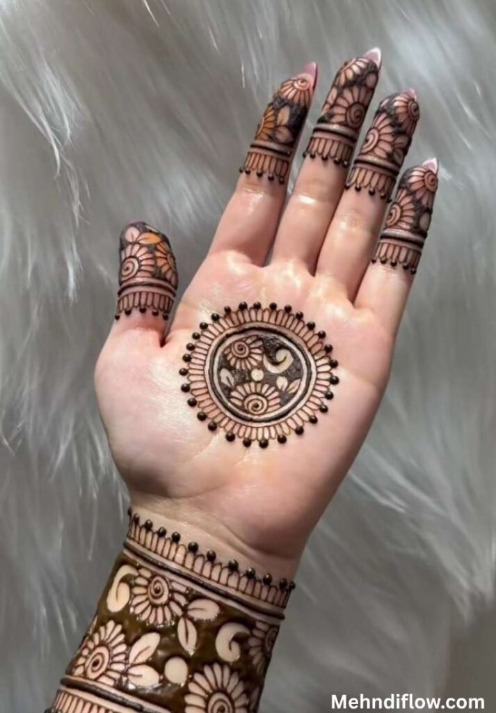 Daily wear circle mehndi design on the palm featuring a detailed floral paisley tikki pattern and matching intricate wrist band.