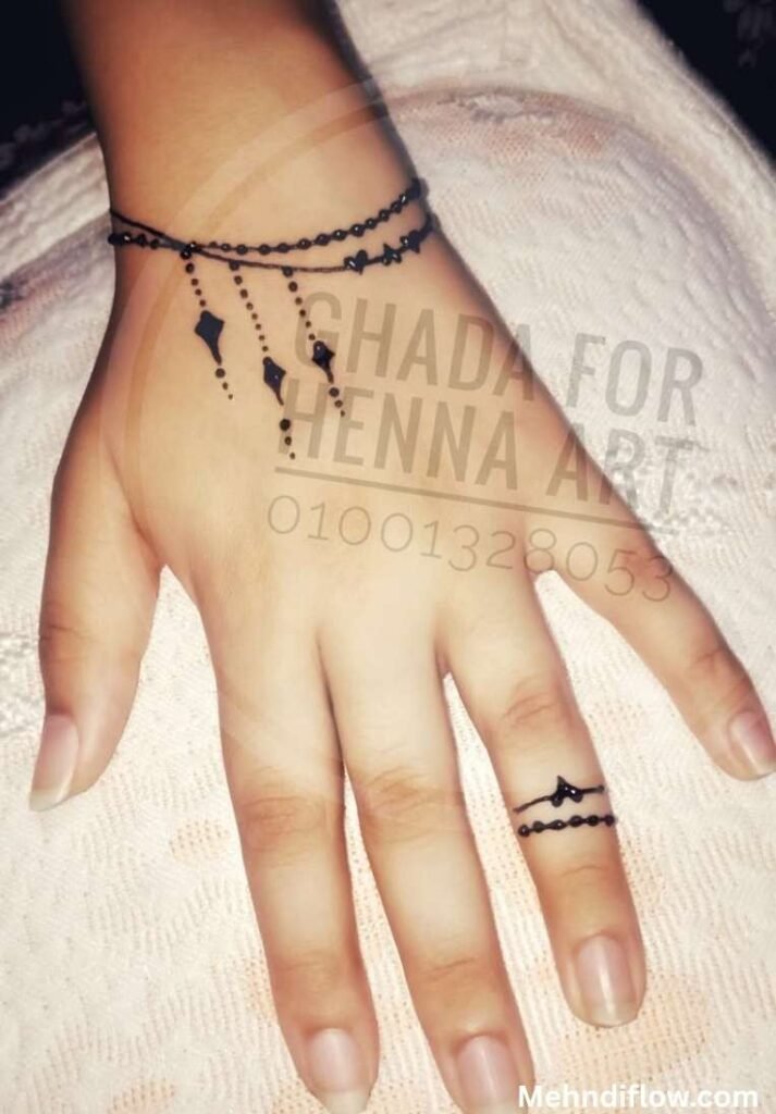 Minimalist jewelry-style mehndi design featuring a delicate dot bracelet around the wrist with dangling diamond charms and a matching fine-line henna ring on the finger.