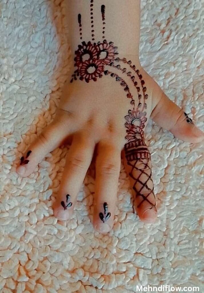 Simple children's mehndi design featuring a floral wrist motif connected by a curved dotted line to a criss-cross patterned pinky finger, with small botanical accents on the fingertips.