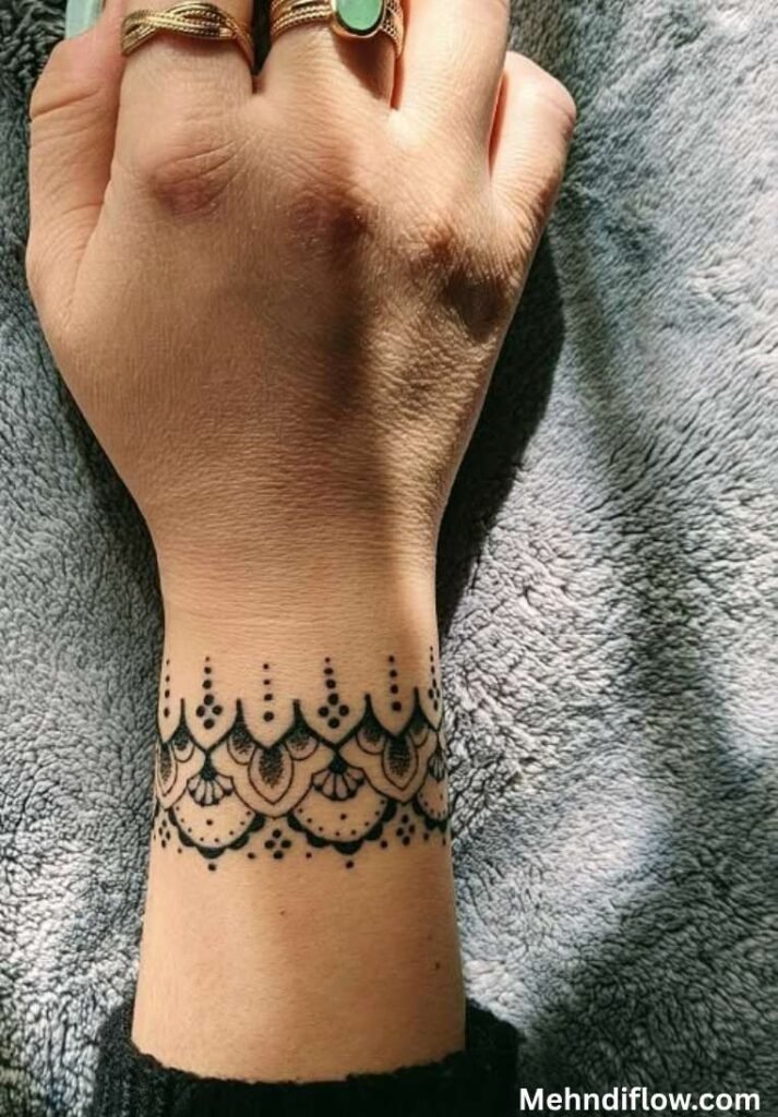 Intricate mandala cuff henna bracelet design on a wrist with scalloped arches and fine dot detailing.