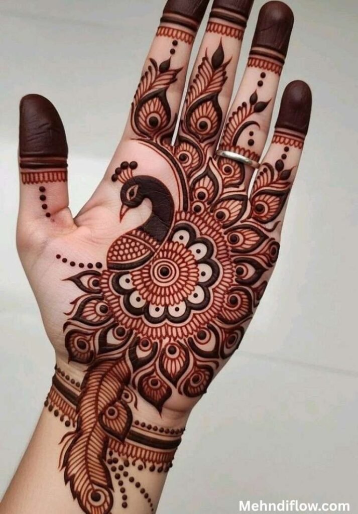 Elaborate peacock henna pattern on the palm featuring detailed mandala accents and dramatic, shaded feather motifs.