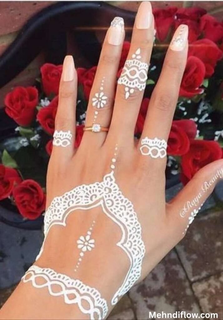 Elegant jewelry-style white henna design showcasing a scalloped wrist cuff, a delicate arched hand piece with subtle dotted details, and ornate patterned finger rings.