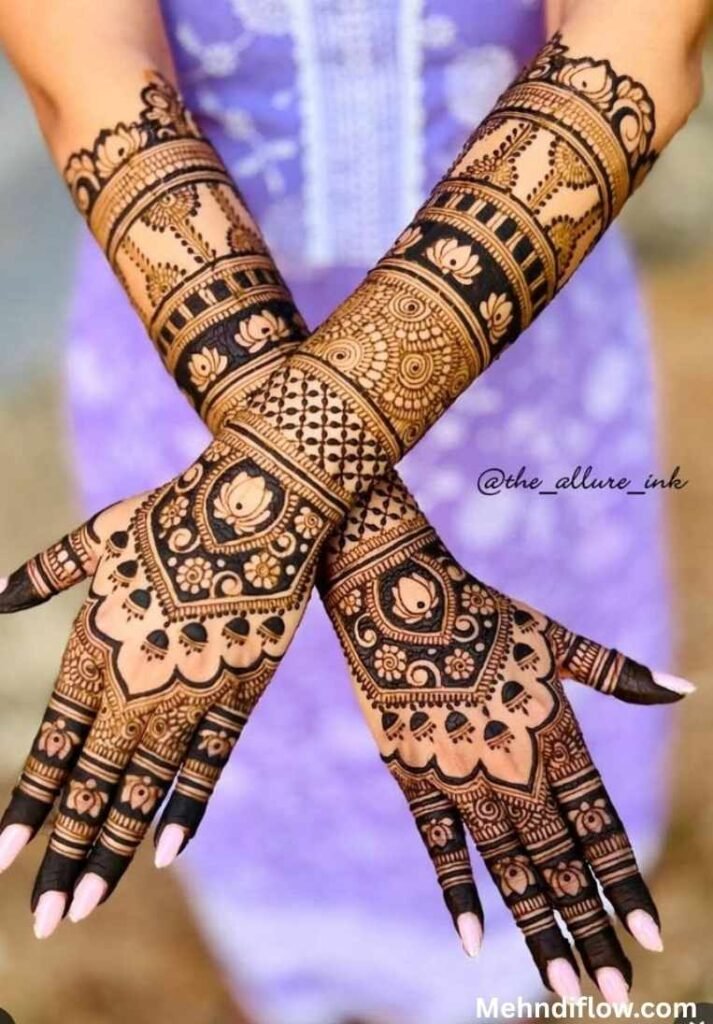 Elegant bridal mehndi design on crossed hands and forearms, featuring prominent lotus motifs, negative space shading, a central grid pattern, and hanging dome-like jhumka details on the back of the hands.