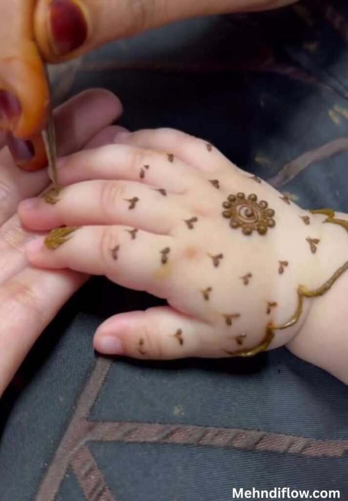 Minimalist baby girl mehndi design showcasing a small central circular motif surrounded by scattered traditional dots and minimal geometric patterns on the back of the hand.