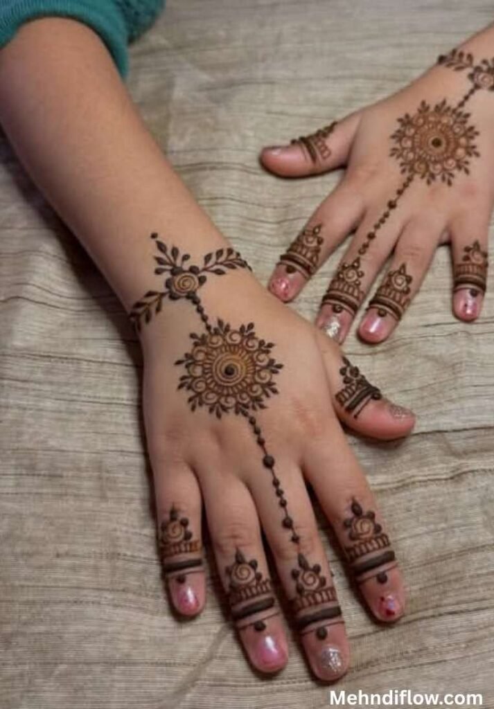 Simple traditional mehndi design for baby girls featuring a central circular mandala connected by delicate dotted chains to a patterned wristband and decorated fingertips.