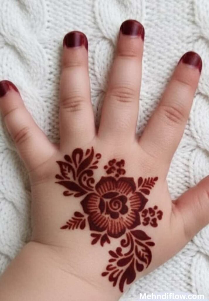 Fast single flower kids mehndi design showcasing solid henna fingertips and a bold, darkly shaded central rose motif surrounded by delicate leaves on the back of the hand.

