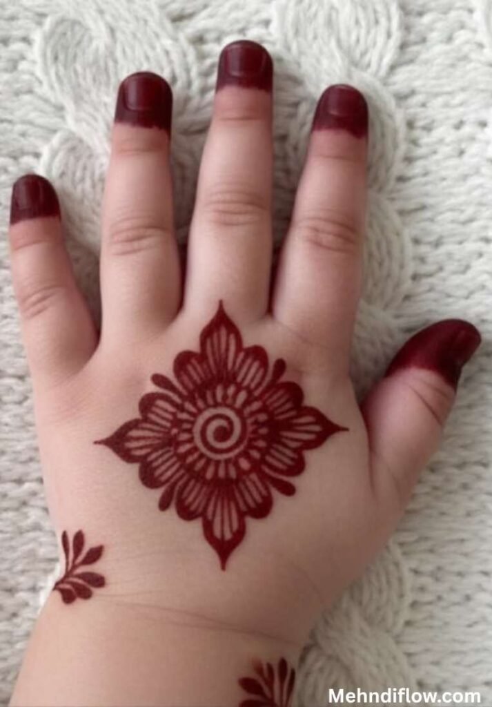 Quick and simple single flower mehndi design for children featuring traditional solid colored fingertips and a symmetrical, diamond-shaped mandala with a spiral center on the back of the hand.

