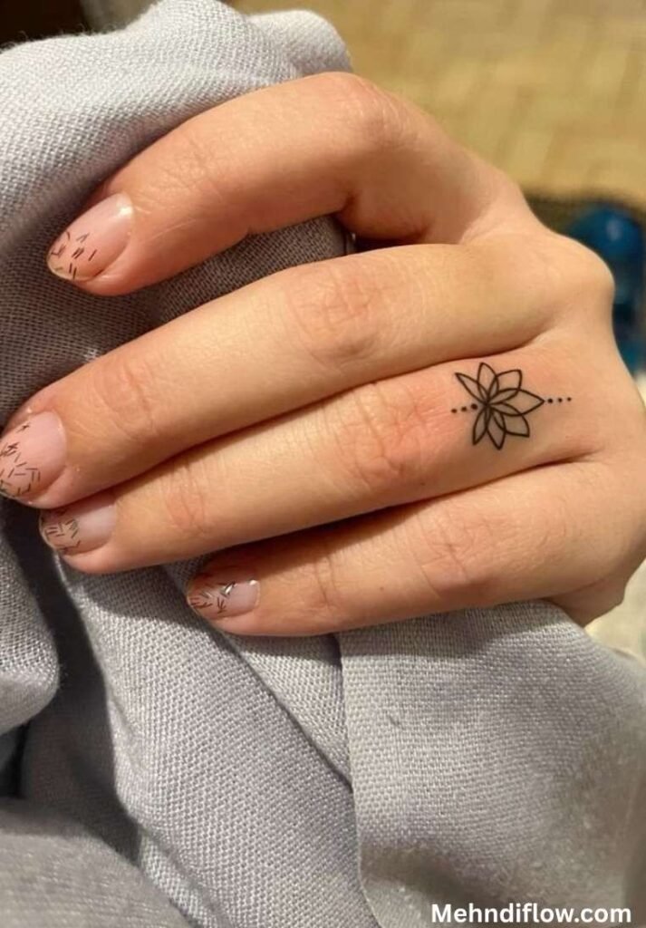 Minimalist single lotus mehndi design on the side of the index finger with a small dotted line.