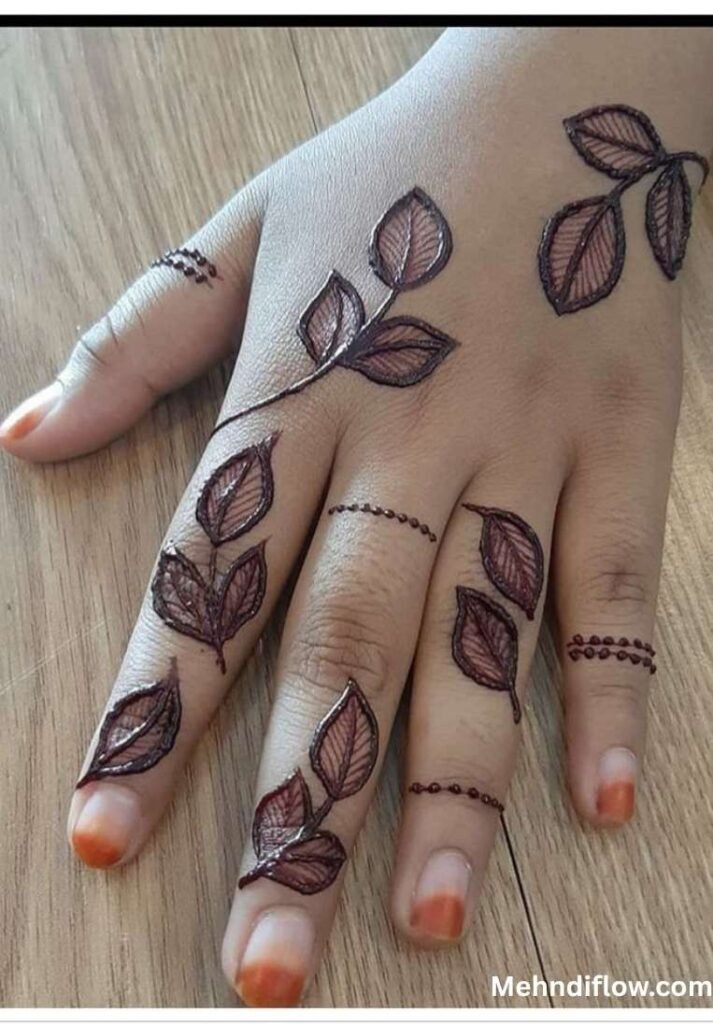 Minimalist raj mehndi design showcasing scattered leafy branches across the back of the hand and traditional dotted band accents on the fingers.