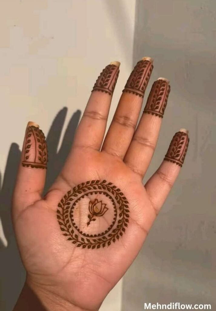 Centered palm tikki mehndi design with a minimalist lotus flower motif enclosed by concentric leaf circles and fully shaded fingertips.