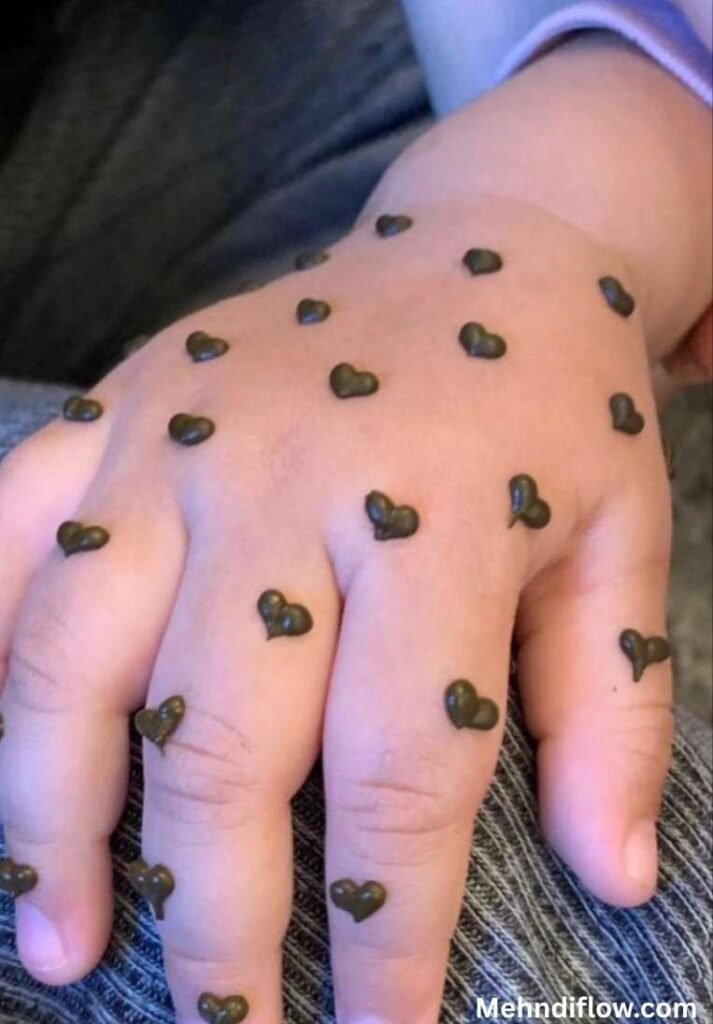 Fast single flower kids mehndi design showcasing solid henna fingertips and a bold, darkly shaded central rose motif surrounded by delicate leaves on the back of the hand.

