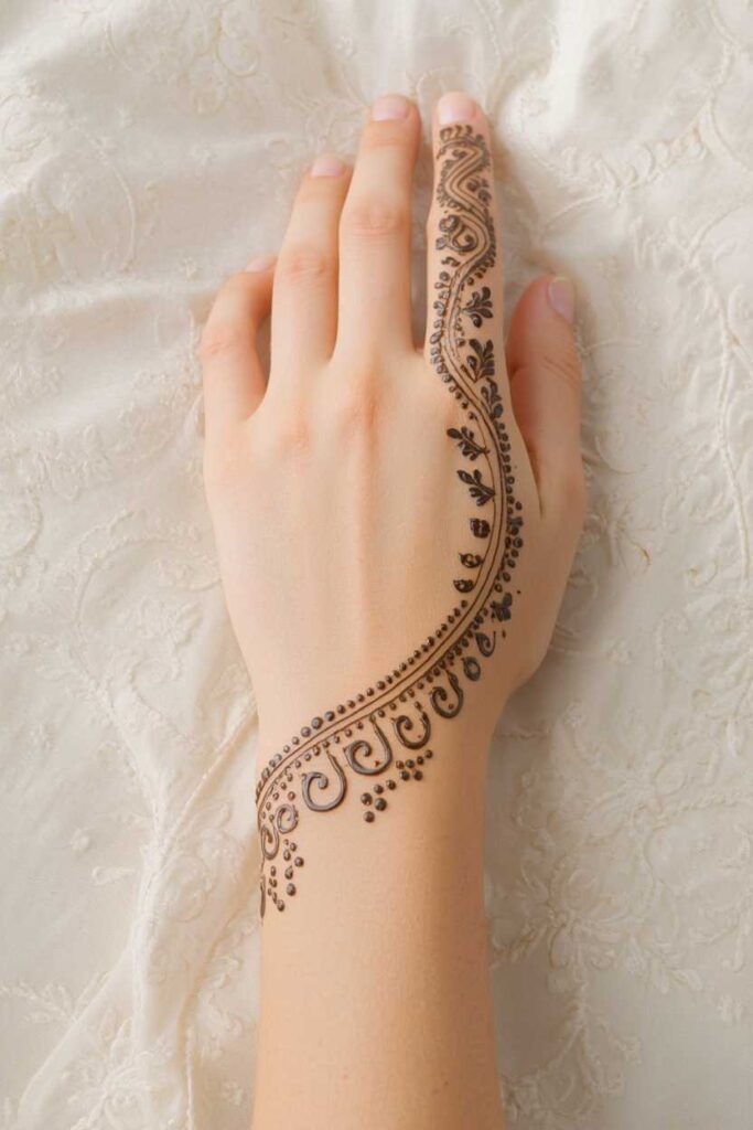  Flowing boys back-hand mehndi design extending from the wrist to the finger.